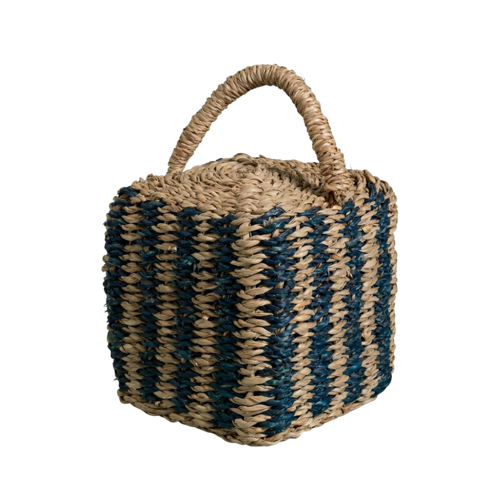 A square woven straw bag with a single top handle, featuring alternating vertical stripes of natural tan and dark teal blue.