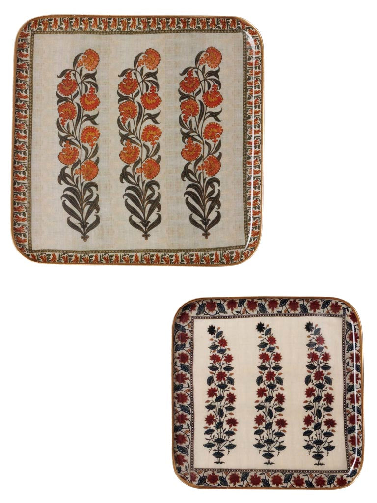 Two rectangular decorative trays with rounded corners on a white background. The top tray has three vertical floral motifs in orange and dark brown on a cream base, with an ornate multicolor border.