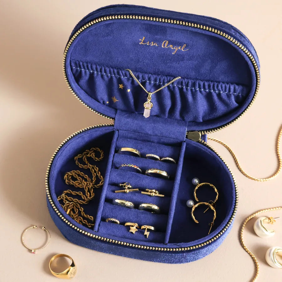 Blue jewelry case with gold jewelry on a beige background