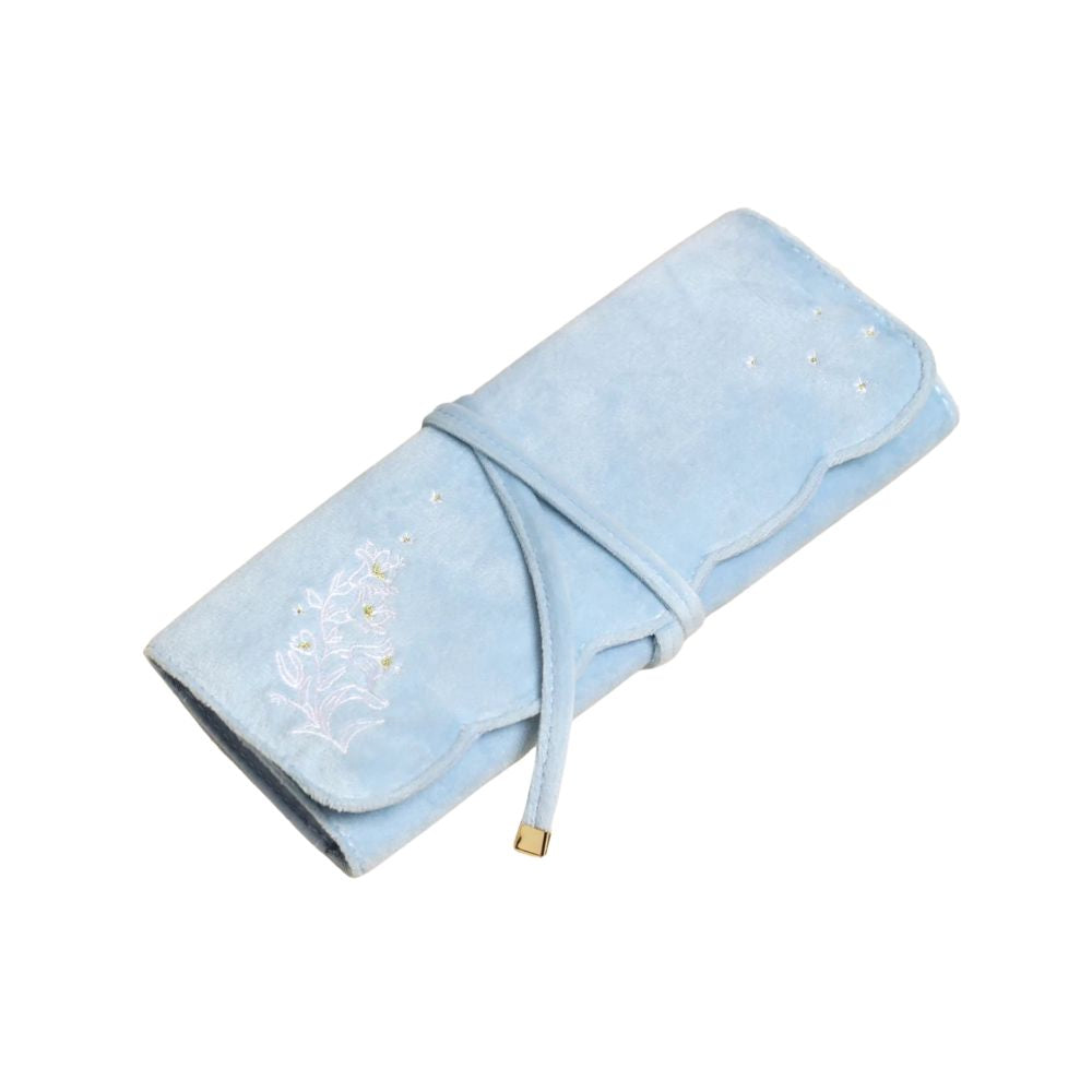 A light blue velvet jewelry organizer roll-up case with white floral embroidery, small rhinestone accents, and a tie closure on a plain white background.