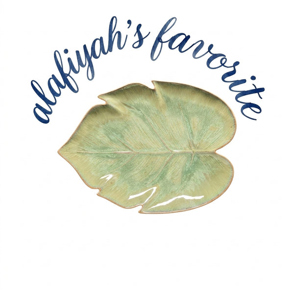 A glossy ceramic leaf-shaped plate in pale green with a subtle gold-toned rim, centered on a white background beneath the blue script text 'alafiyah's favorite'.