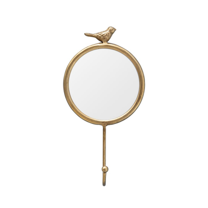 A round wall mirror with a gold-toned metal frame, featuring a small bird perched on the top edge and a hanging hook at the bottom, shown against a plain white background.