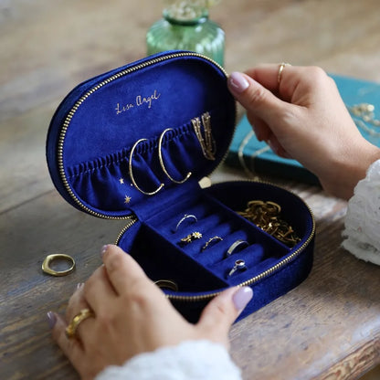 Blue jewelry case with gold jewelry held by a person on a wooden surface