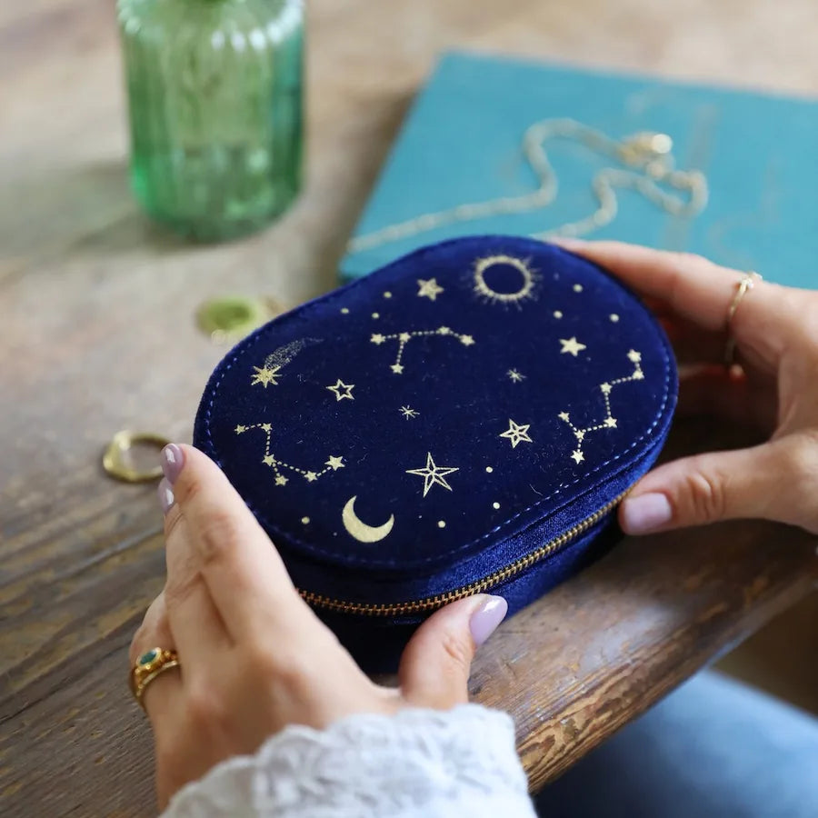 Navy blue pouch with star and constellation patterns held by a person on a wooden surface.