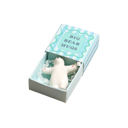 A white bear-shaped squeeze hug toy nestled inside its light blue and white striped gift box, which features the text 'BIG BEAR HUGS' on the lid.
