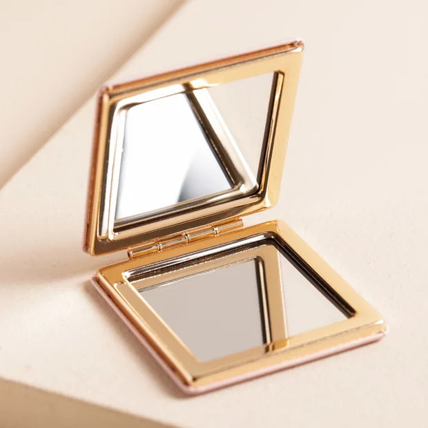 Gold compact mirror on a beige background