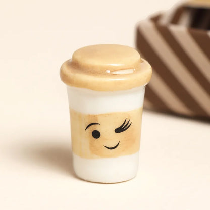 Small ceramic cup with a smiling face design on a beige background.