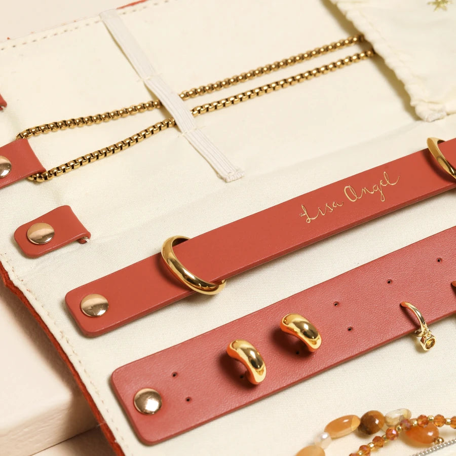 Red leather bracelets with gold accents on a beige surface