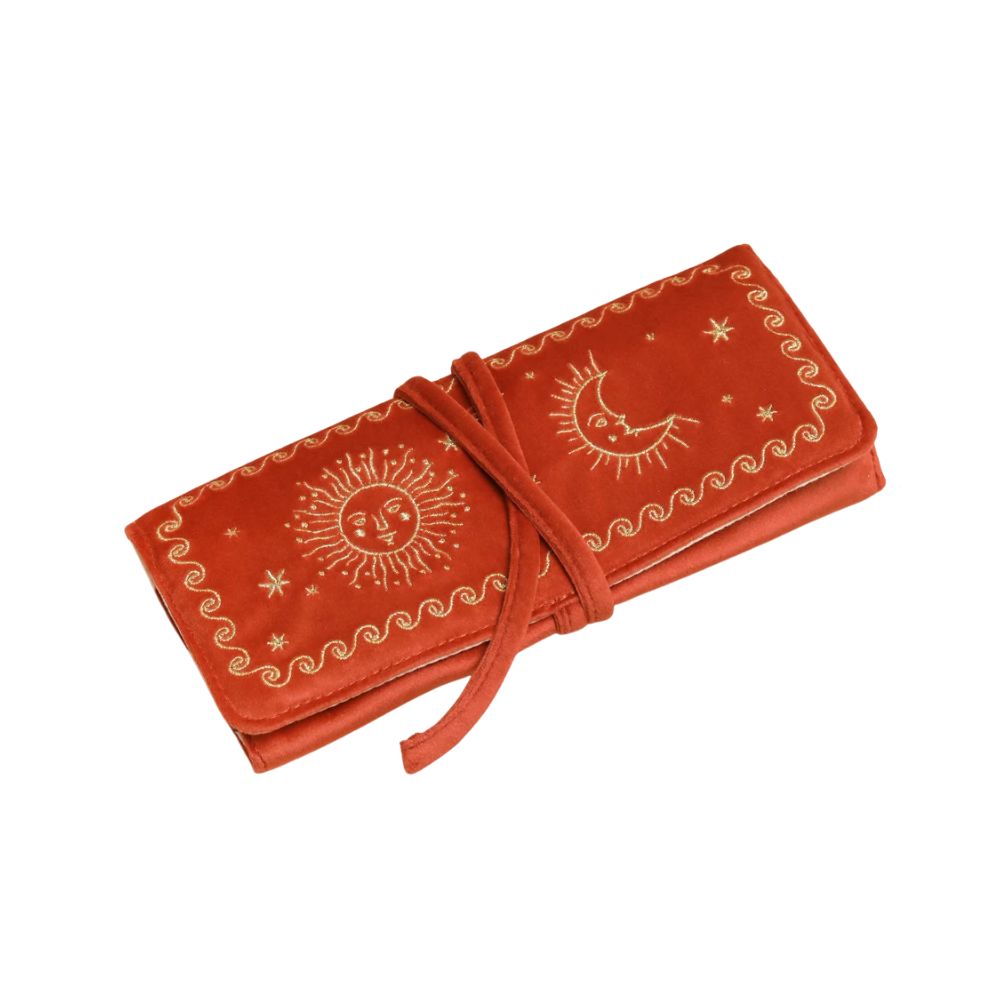 A terracotta orange velvet journal cover featuring gold celestial embroidery of a sun, moon, and stars, wrapped with a matching tie strap on a white background.