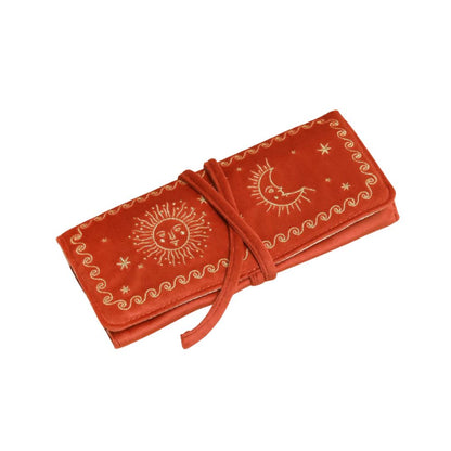 A terracotta orange velvet journal cover featuring gold celestial embroidery of a sun, moon, and stars, wrapped with a matching tie strap on a white background.